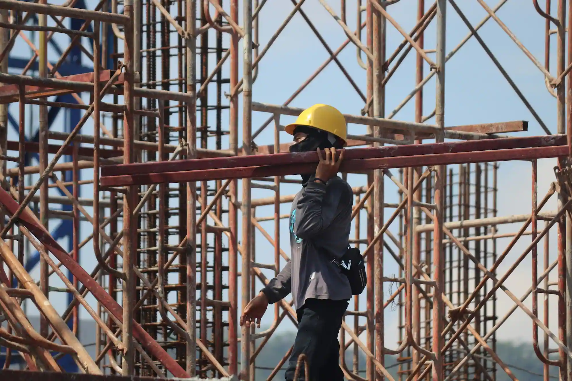 Hayward Scaffolding Rental worker transporting scaffold beam at active job site